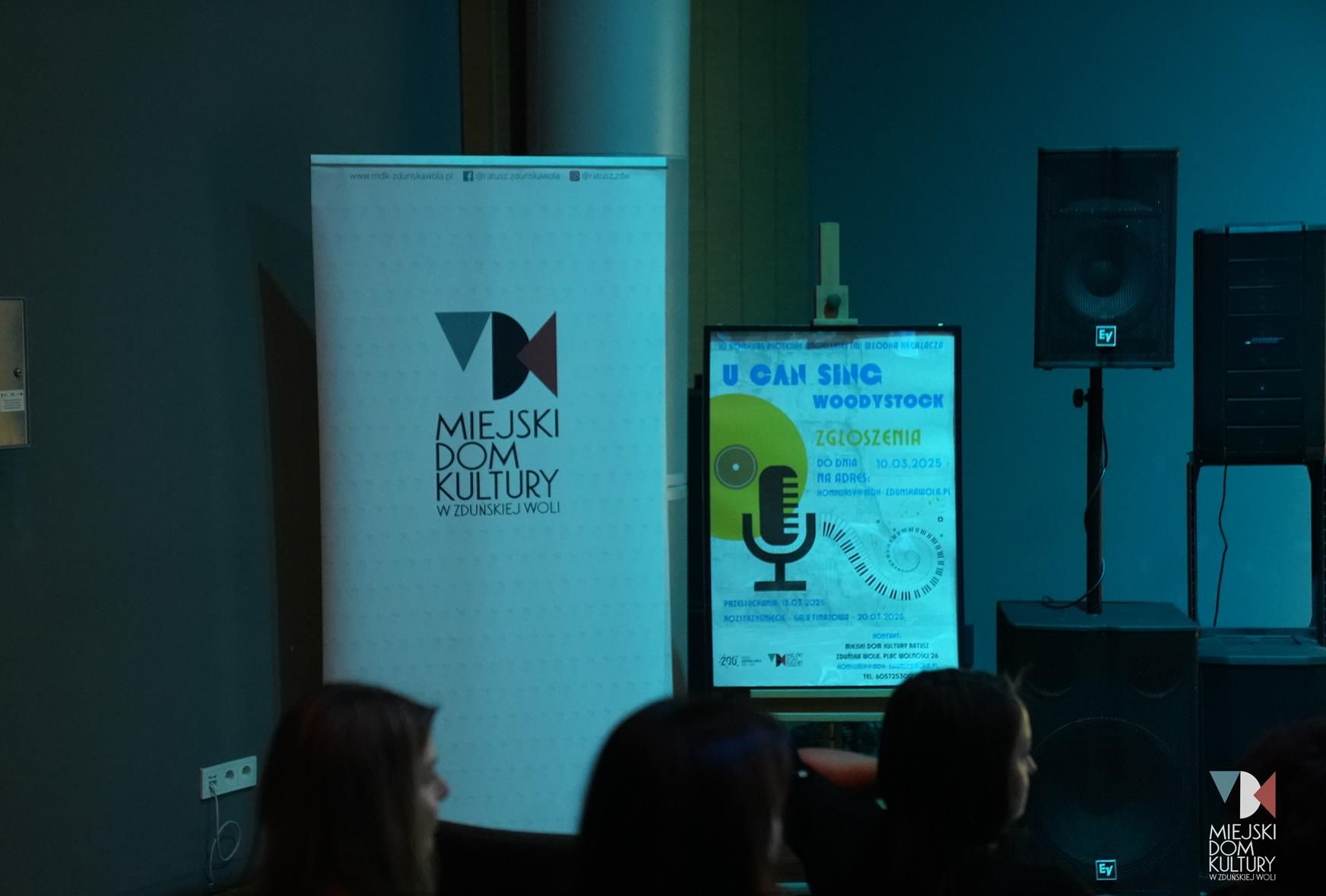 zdjęcie przedstawia rollup i sztalugę z plakatem zapowiadającym konkurs piosenki angielskiej U Can Sing