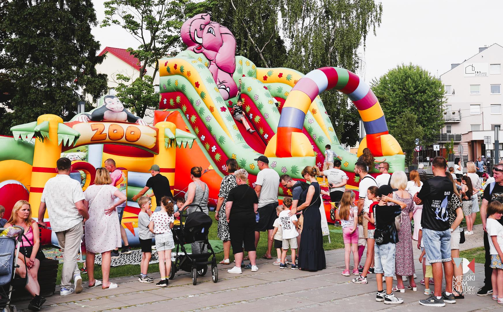 zdjęcie przedstawia grupę ludzi, kilkadziesiąt osób na tle kolorowego dmuchańca