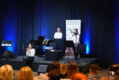zdjęcie przedstawia trzy kobiety na scenie w sali kameralnej, kt&oacute;re zaprosiły najmłodszych na koncert Chopinobajka