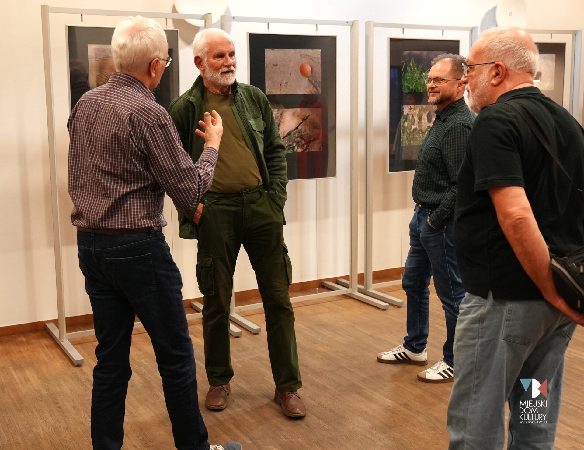 zdjęcie przedstawia trzech mężczyzn na wernisażu wystawy fotografii