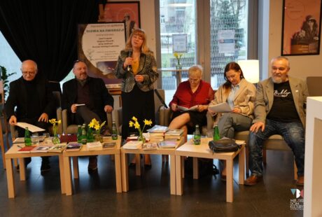 Zdjęcie przedstawia sześć os&oacute;b siedzących za stolikiem kawowym w Kawiarni Literackiej Ratusza