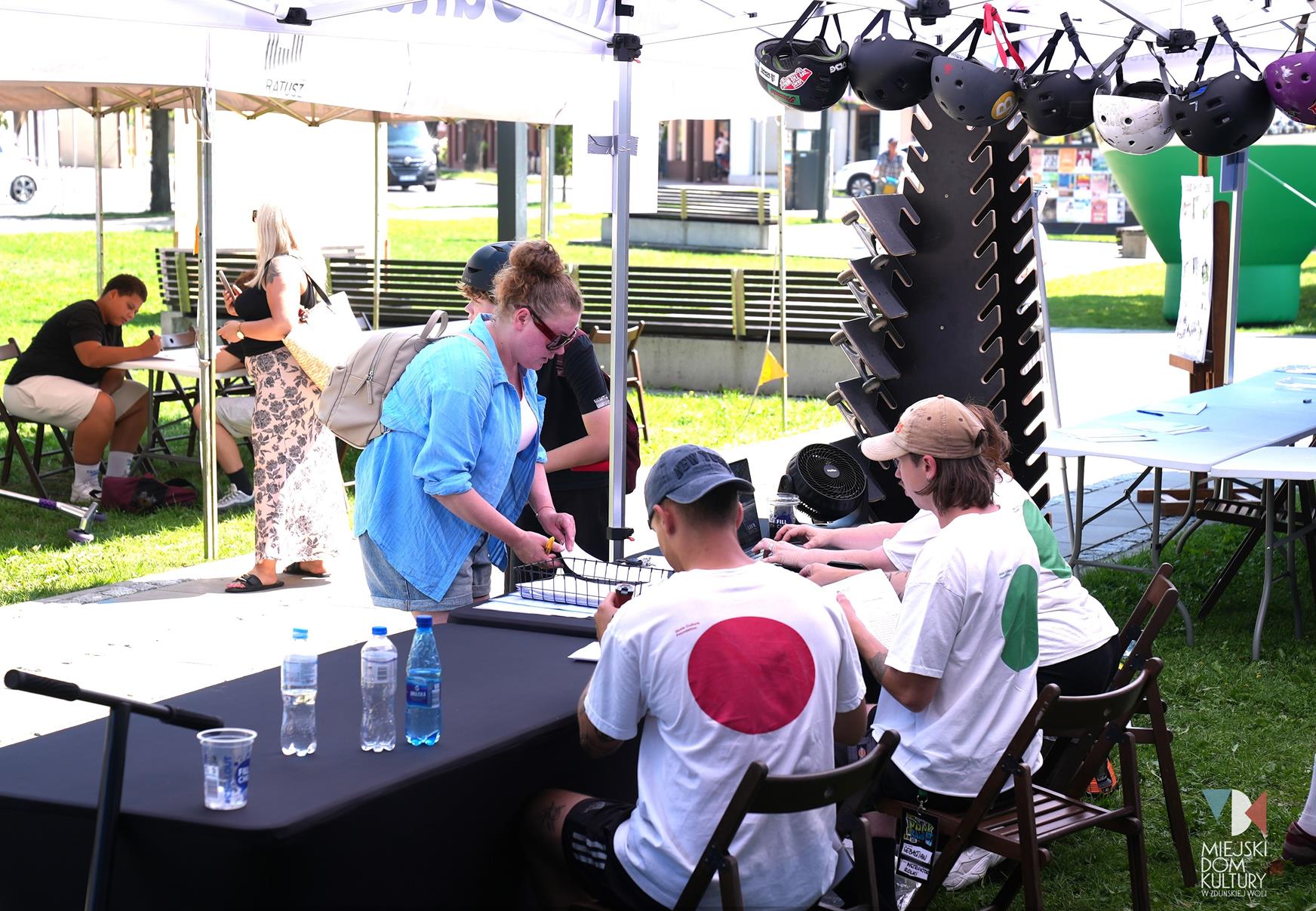 zdjęcie przedstawia cztery osoby, trzy w białych koszulkach z kolorowymi kółkami na plecach, zielonymi, czerwonymi , i kobietę w niebieskiej koszuli