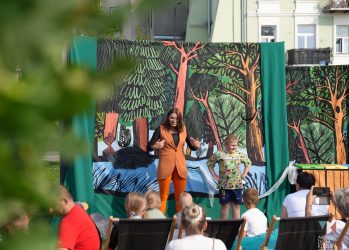 zdjęcie przedstawia dzieci i aktorkę grupy Mozaika w plenerze, przed Ratuszem
